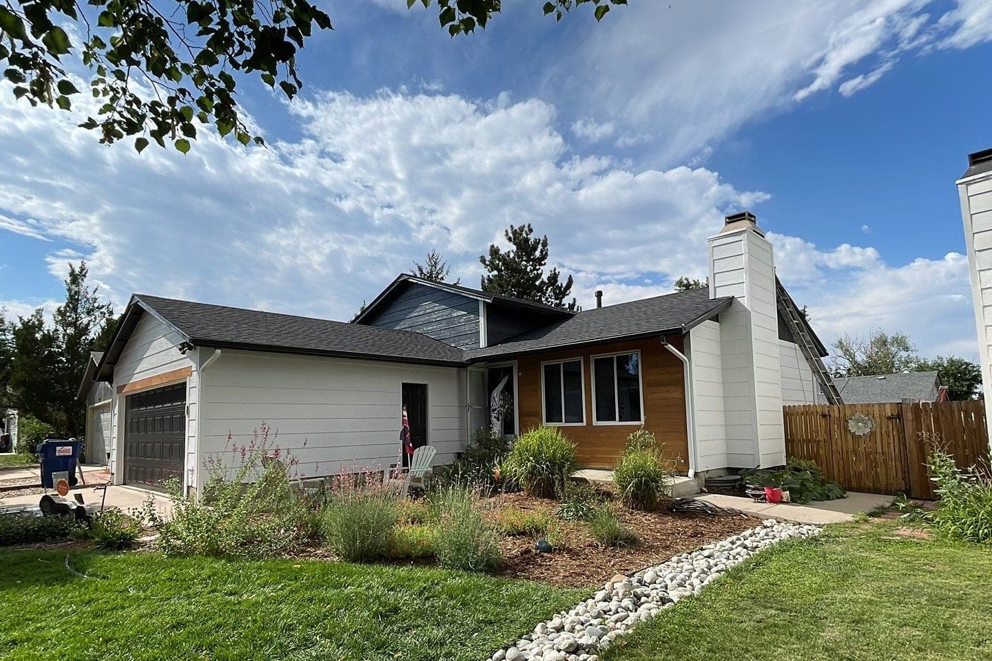 A finished ranch house with white siding, a navy gable, cedar accents and a new roof